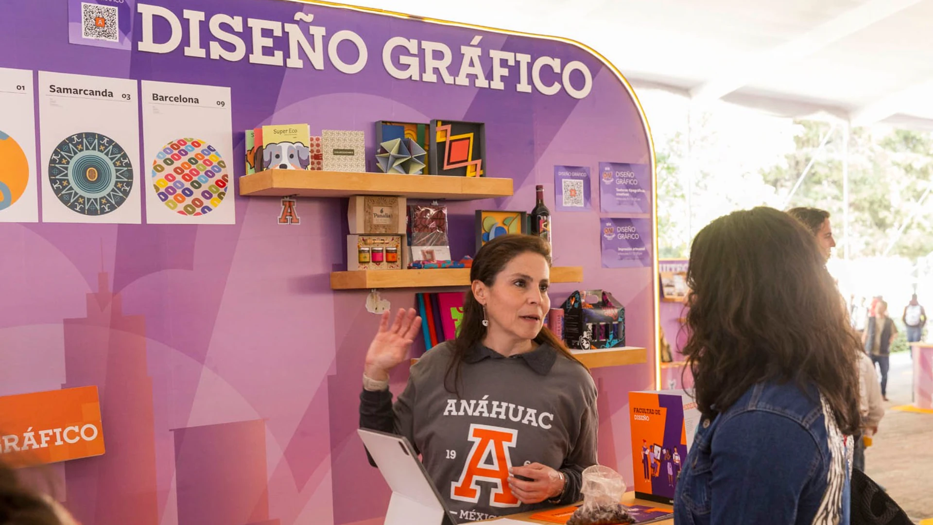 Estudiante preguntando cosas que debería saber antes de estudiar diseño gráfico en un stand de carrera Anáhuac