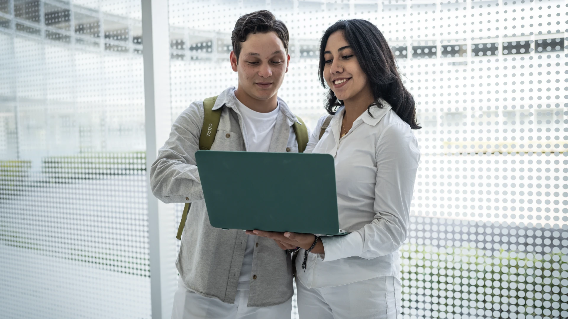 Estudiantes mirando pantalla de laptop en pasillo universidad anahuac