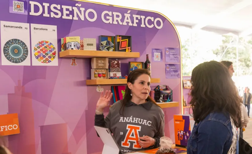 Estudiante preguntando cosas que debería saber antes de estudiar diseño gráfico en un stand de carrera Anáhuac