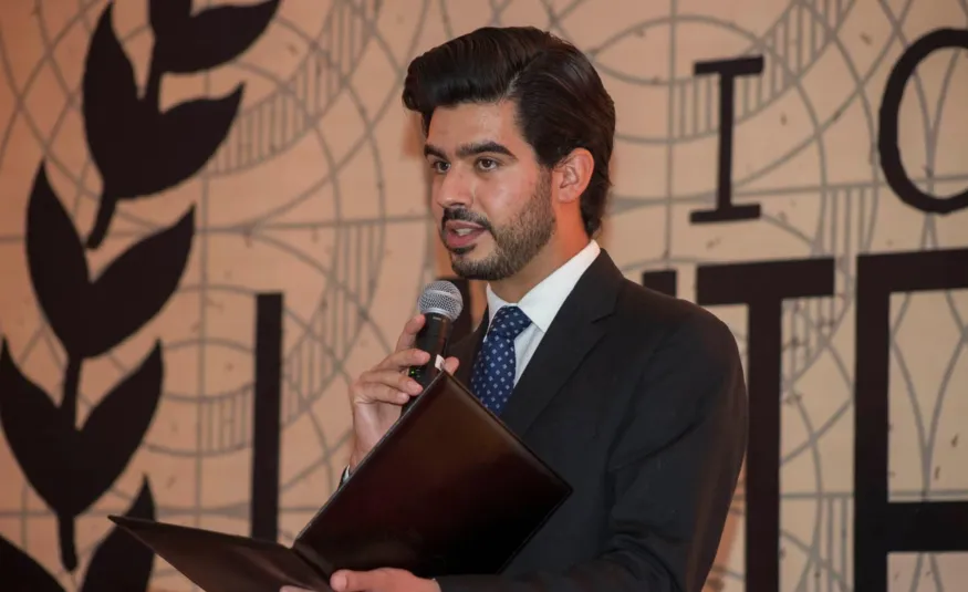 Estudiante de la anáhuac con traje dando un discurso diplomático frente a un foro