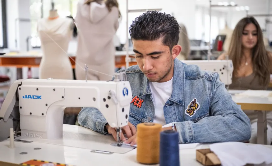 Estudiante de diseño de moda cosiendo una prenda con textiles sustentables