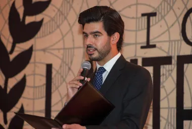 Estudiante de la anáhuac con traje dando un discurso diplomático frente a un foro