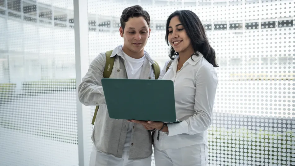 Estudiantes mirando pantalla de laptop en pasillo universidad anahuac