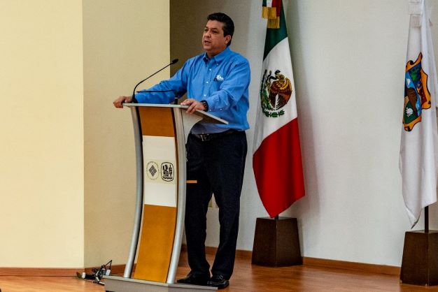 El gobernador Cabeza de Vaca, con camisa azul, hablando al podio esbelto del auditorio David Gómez.