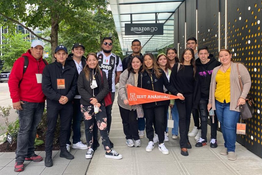 Alumnos del IEST con un banderín, afuera de la sede de Amazon.