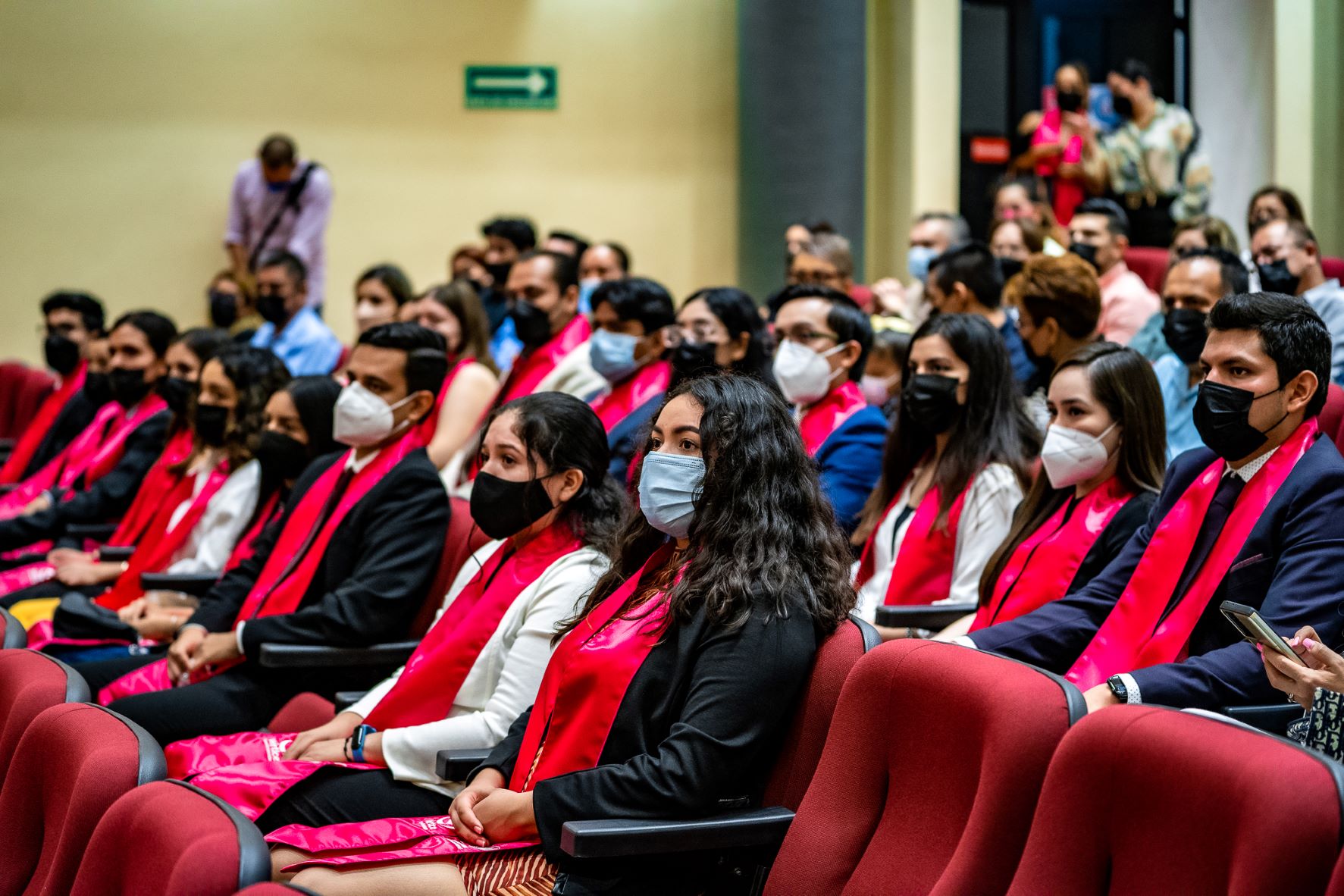 Alumnos de vértice en la graduación, observando hacia el escenario.