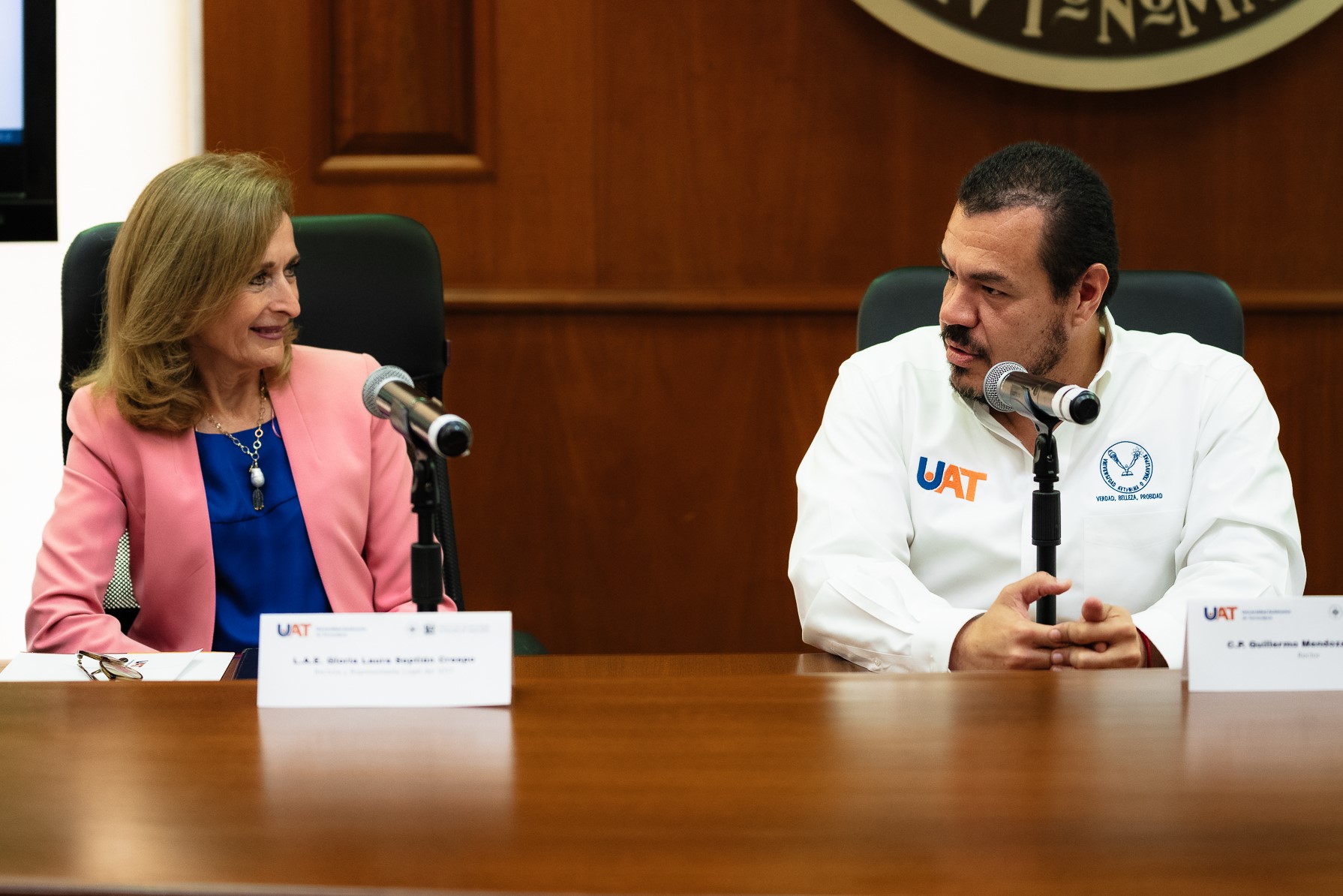 La Rectora del IEST, vestida de rosa, observa al Rector de la UAT, quien trae una camisa blanca.