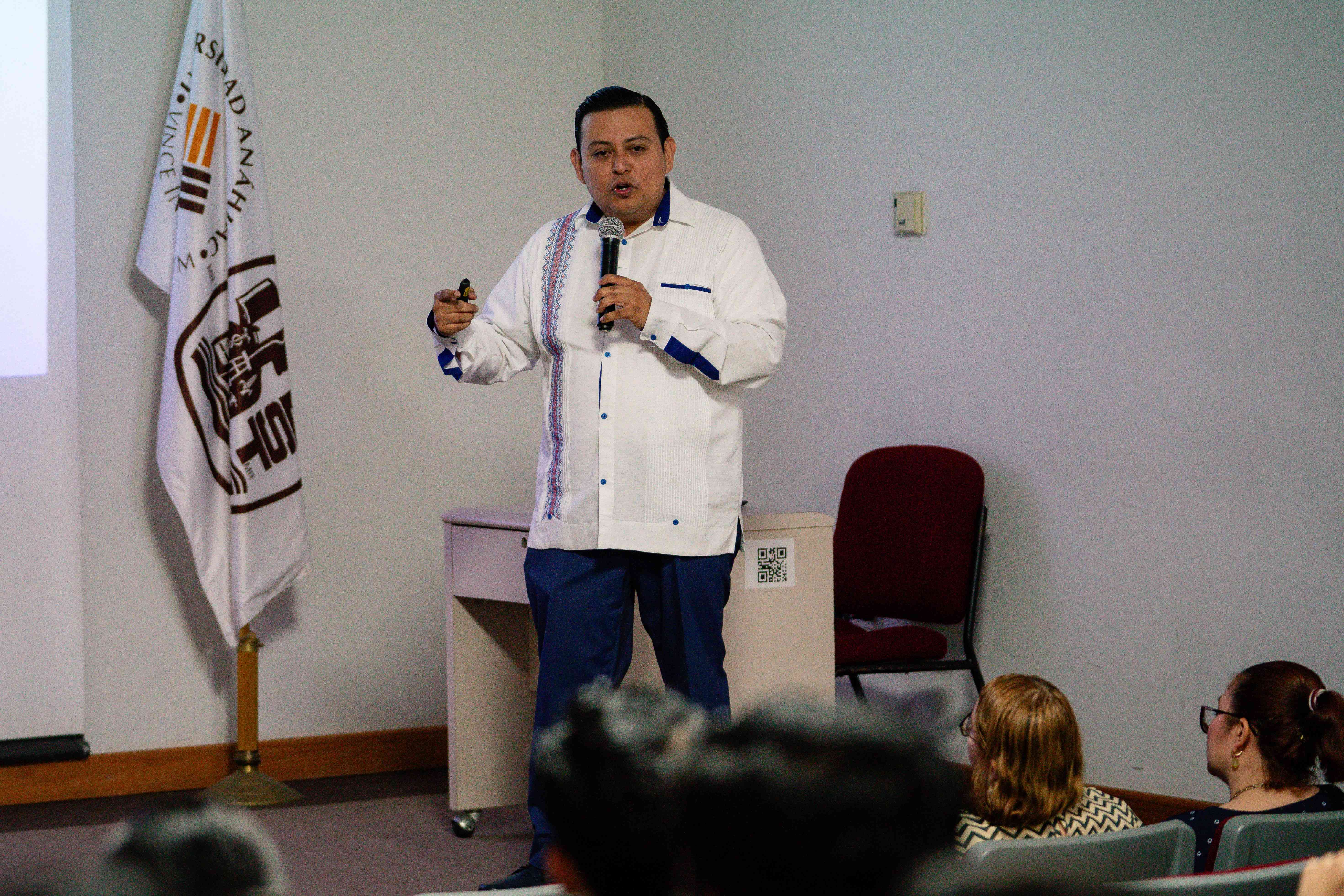 Gustavo Hernández, con una guayabera blanca, ofreciendo una conferencia en el IEST Anáhuac.