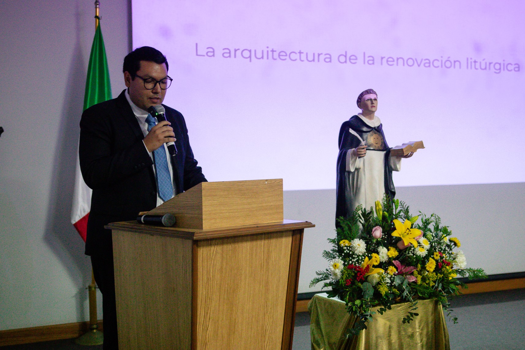 Joven de Teología, dando un mensaje, junto a la estatua de Santo Tomás de Aquino.