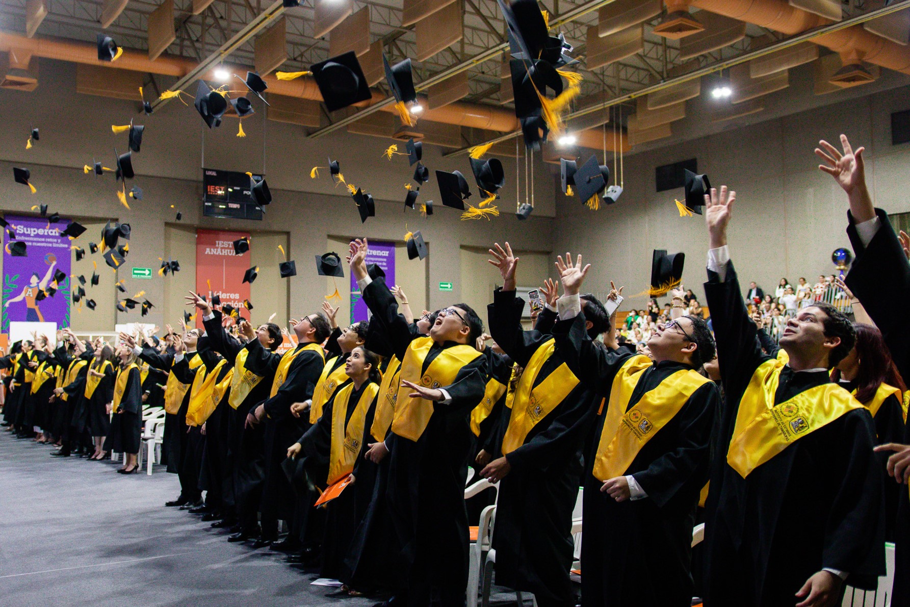 Alumnos de profesional aventando sus birretes. Graduación Humanidades y Exactas.