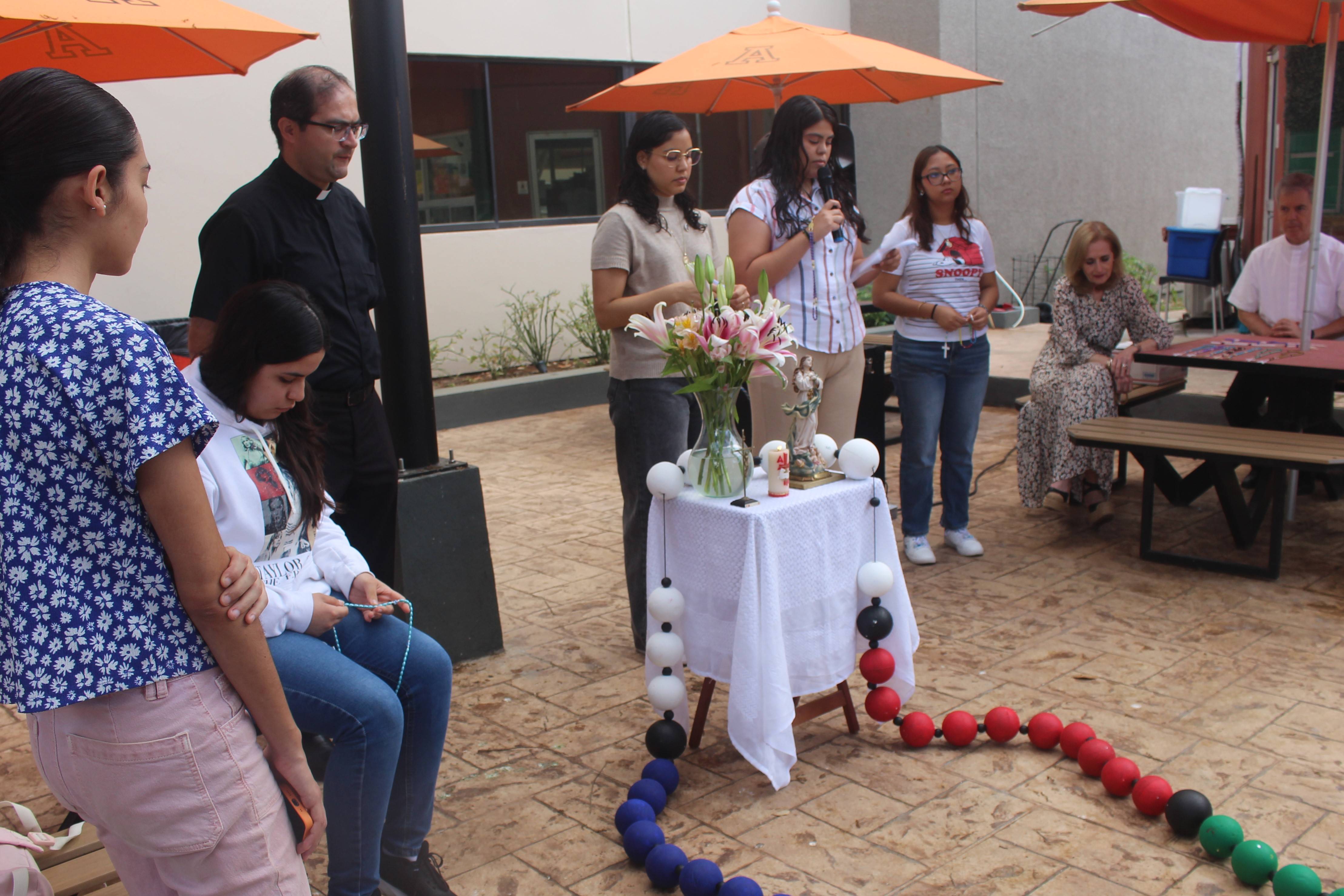 Alumnos y sacerdotes legionarios rezando el rosario en la plazoleta de cafetería.