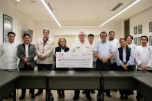 Autoridades académicas y alumnos de Gastronomía entregando un cheque.