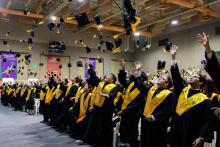 Alumnos de profesional aventando sus birretes. Graduación Humanidades y Exactas.